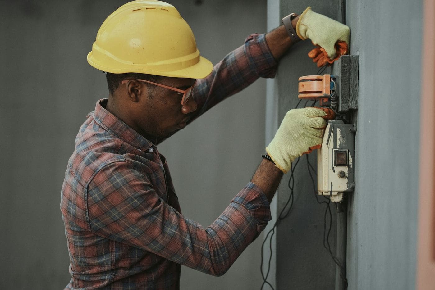 Un technicien casqué et ganté intervient sur un boîtier électrique
